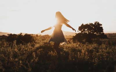 A woman walks joyfully through nature with the golden sun in background